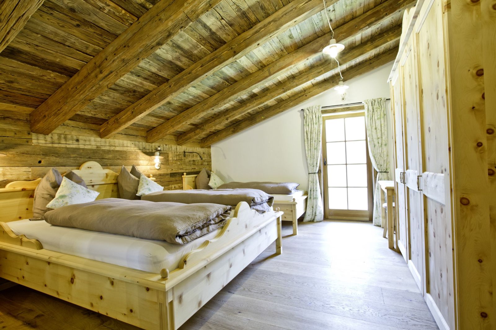 Schlafbereich mit Holzbetten und Balkonzugang auf der Martenalm