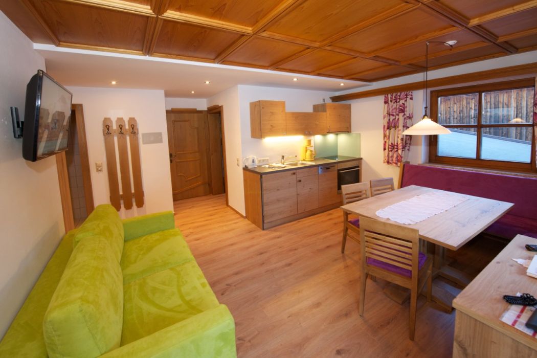 Wohnküche am Martenhof mit grünem Sofa und Esstisch