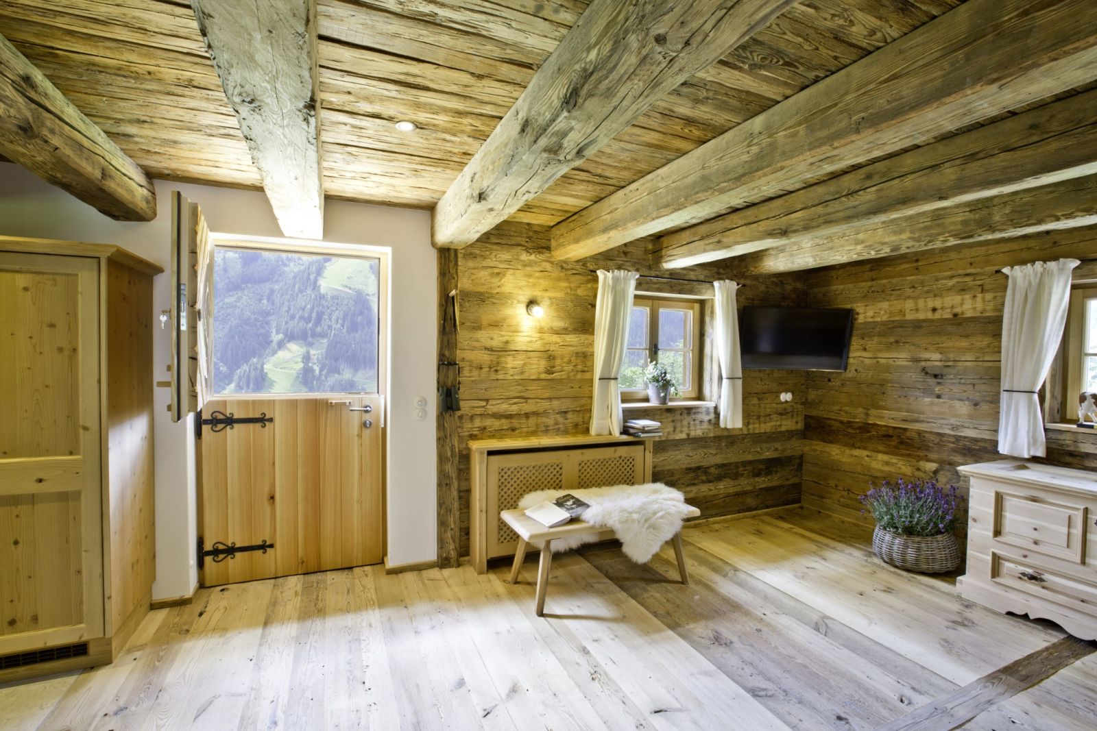 Wohnzimmer mit Fernseher und Holzdecke auf der Martenalm